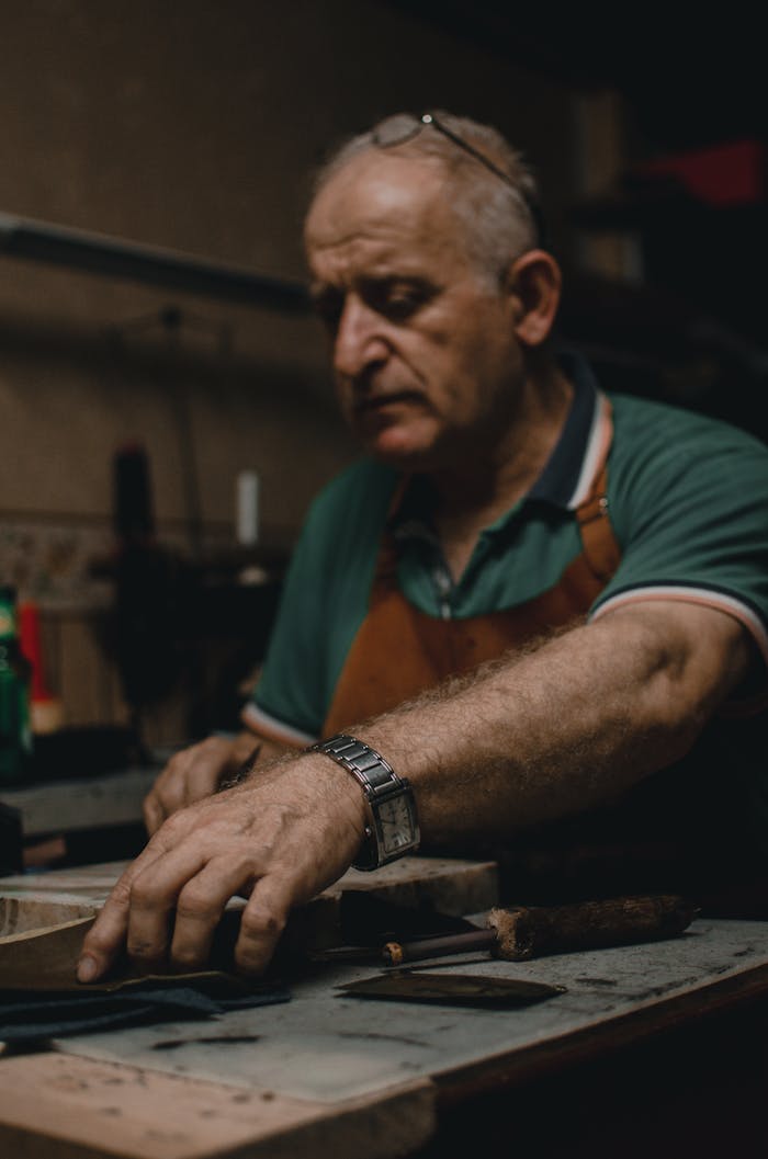 Elderly craftsman concentrating on handmade projects in a traditional workshop setting.