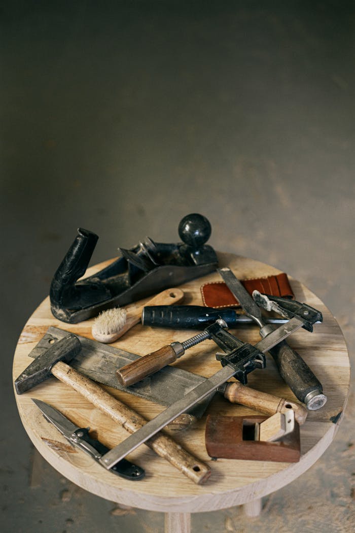 Collection of vintage carpentry tools arranged on a round wooden table.