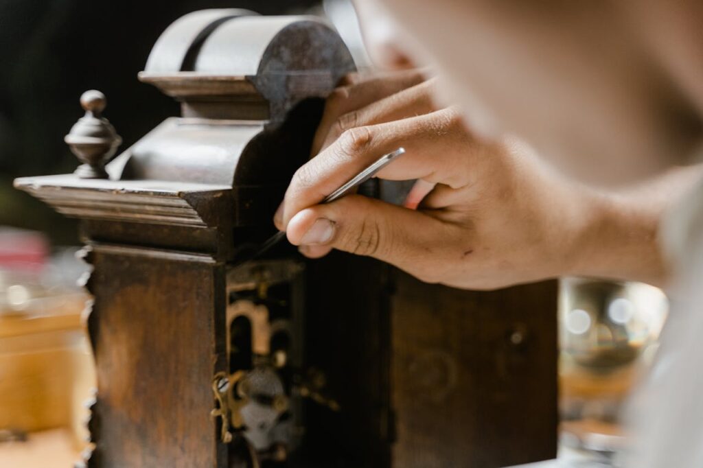 Close-up of hands skillfully restoring an antique wooden clock, highlighting craftsmanship.